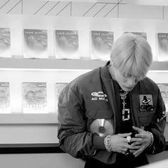 a young man is looking at his cell phone while standing in front of some posters