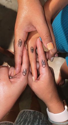 two people holding hands with small tattoos on their fingers and the other hand above them