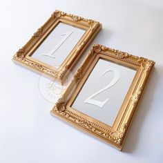 two gold frames with the number one and 2 on them are sitting next to each other