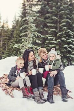 a group of people sitting on top of a snow covered ground next to evergreen trees