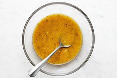 a bowl of soup with a spoon in it on a white counter top, ready to be eaten