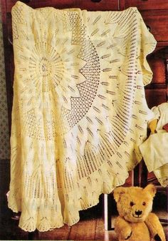 a teddy bear is sitting next to a crocheted blanket on a chair in front of a dresser