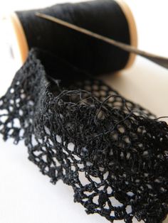 a spool of thread next to a piece of black lace