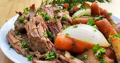 a white plate topped with meat and veggies on top of a wooden table