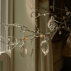 a branch with leaves hanging from it next to a window