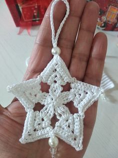 a hand holding a white crocheted star ornament