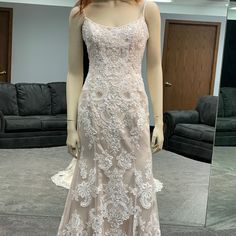 a mannequin wearing a wedding dress in front of a mirror with the reflection of a couch behind it