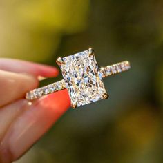 a close up of a person holding a ring with a princess cut diamond on it