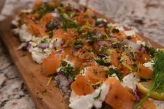 a wooden cutting board topped with lots of food on top of a marble countertop