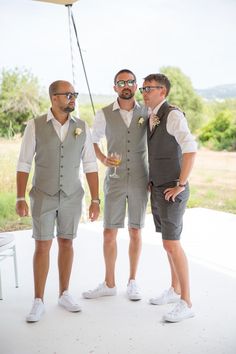 three men standing next to each other in front of a white table with drinks on it