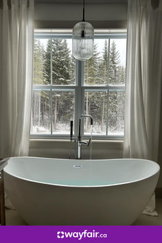 a white bath tub sitting in front of a window next to a curtained wall