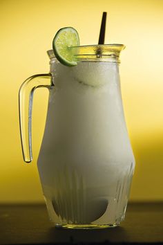 a pitcher filled with ice and a lime slice on the rim, sitting on a table