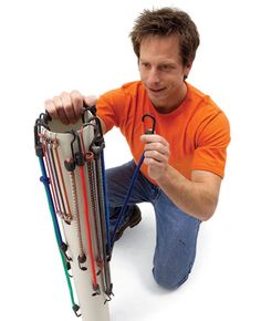 a man sitting on the ground holding a pair of scissors next to a bunch of skis