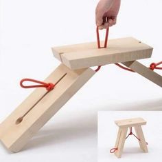 a hand is pulling something from the top of a small wooden structure with red cords