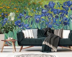 a living room with blue flowers painted on the wall and green couches in front