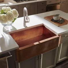 a kitchen sink sitting on top of a counter next to a vase with flowers in it