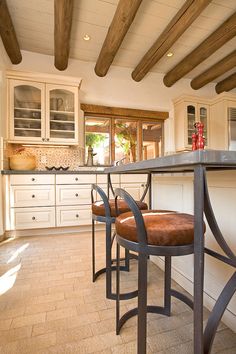 a kitchen with two stools and a bar in the middle, next to an oven