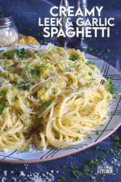 a plate full of pasta and parmesan cheese on a blue tablecloth with the title creamy leeks & garlic spaghetti