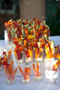 there are many small trays filled with fruit and veggies on the table