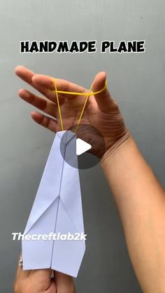 a hand holding an origami plane with the words handmade plane above it