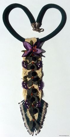 a black and white necklace with purple flowers hanging from it's side on a string