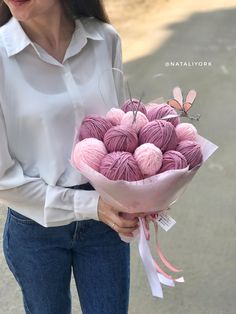 a woman holding a bouquet of pink balls of yarn