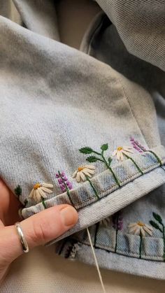 someone is stitching flowers on the side of a pair of jeans