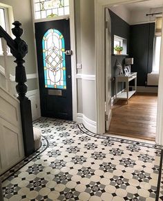 an entryway with black and white tile flooring, stained glass window and door