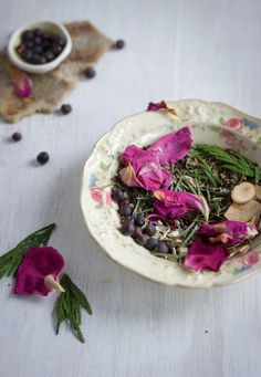 a bowl filled with flowers and herbs on top of a table