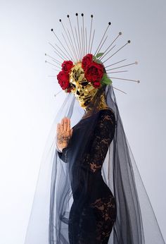 a woman wearing a veil with flowers on her head and holding a red rose in her hand