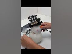 someone is decorating a snowman with a black and white hat