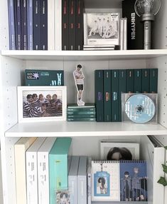 a book shelf filled with lots of books and cds on top of each shelf in front of a clock