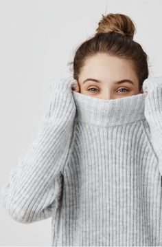 a woman covering her face with the sweater