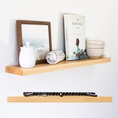 a shelf with some books and other items on it next to a mug, bowl, pen and mirror