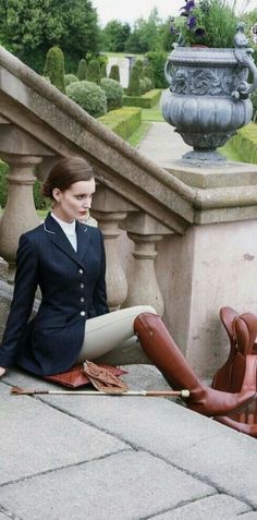 a woman sitting on the ground with her legs crossed and boots in front of her