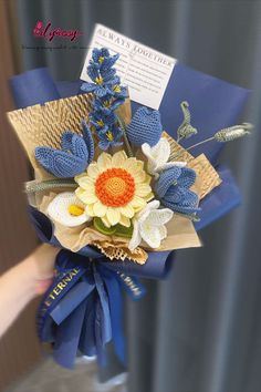 a bouquet of flowers is wrapped in blue and brown paper with a note attached to it