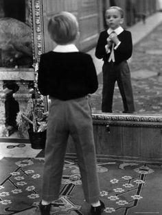 a little boy that is standing in front of a mirror