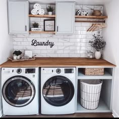 a washer and dryer in a laundry room with white cabinets, wood counter tops and shelves