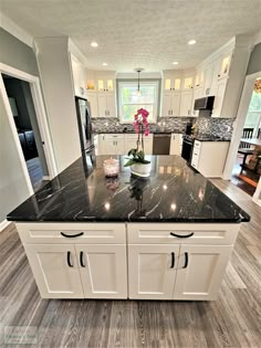 a kitchen with white cabinets and black granite counter tops, along with an island in the middle