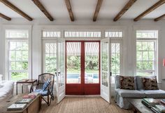 a living room filled with furniture and a red door leading to a swimming pool in the background