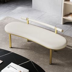 a white bench sitting on top of a carpeted floor next to a book shelf