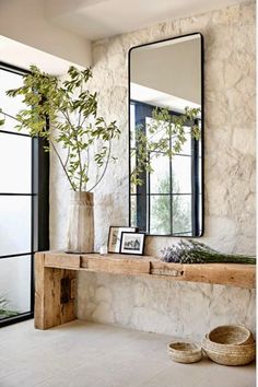 there is a mirror and some plants on the shelf in this room with stone walls