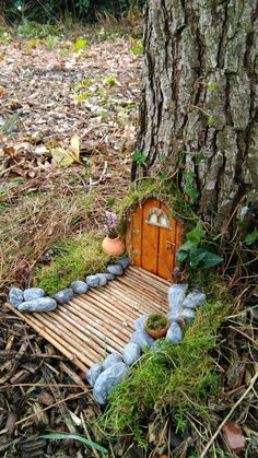 a small house made out of rocks and wood in the woods next to a tree