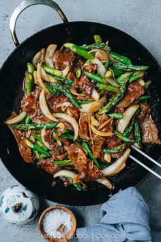 beef and asparagus stir fry in a wok with chopsticks on the side