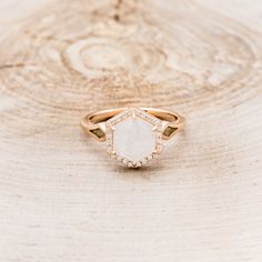 a close up of a ring on top of a wooden table with white and green stones