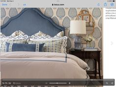 an image of a bed with blue headboard and pillows on the side table in front of it