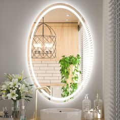 a bathroom with a round mirror on the wall next to a sink and flowers in vases