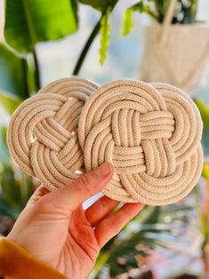 a hand holding two coasters made out of rope