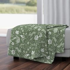 a bed with a green and white comforter on top of it next to a window