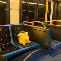 a stuffed animal sitting on the seat of a subway car with other seats and railings